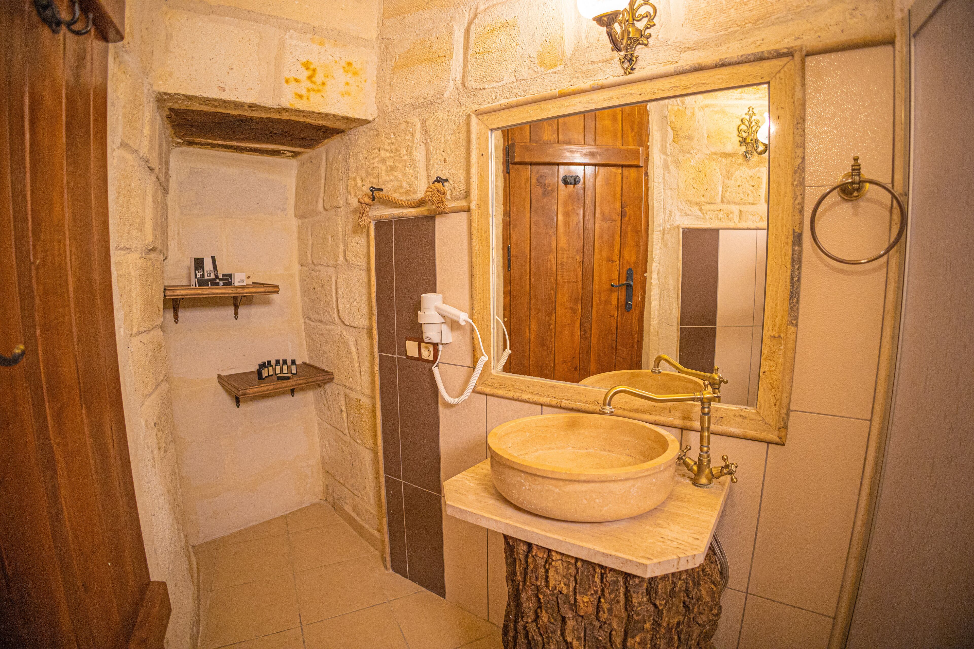 Ein Badezimmer mit Holztür, rundem Waschbecken, Spiegel und Handtuchhalter.