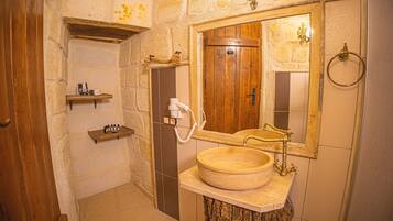 Ein Badezimmer mit Holztür, rundem Waschbecken, Spiegel und Handtuchhalter.
