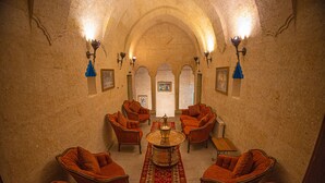 A room with a central round table, four armchairs, a small table, and a patterned rug.