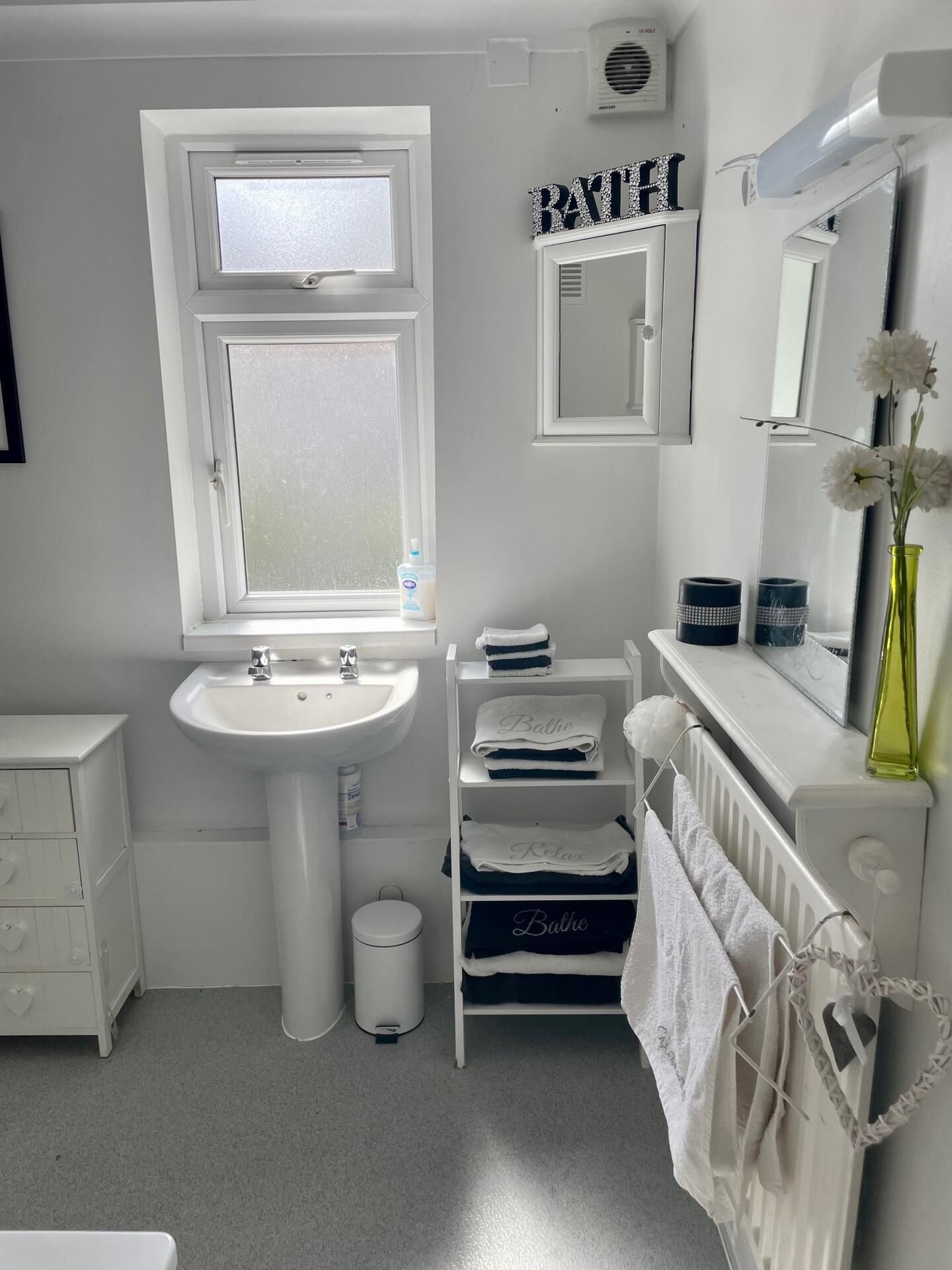 A modern bathroom with a white sink, a window, a mirror, and a towel rack.