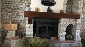 Un camino in pietra con mensola in legno, un divano in pelle verde e una parete in pietra.