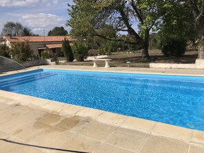 Una piscina rectangular con agua azul cristalina, rodeada de baldosas color beige.