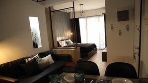 A modern hotel room with a dining area, a sofa, and a bed. - Super Stylish Apartments in the heart of Athens (Athens)