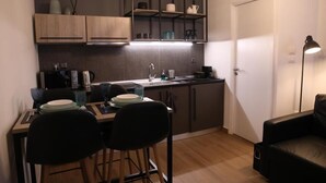 A compact kitchen with a dining area, a black leather couch, and a door. - Super Stylish Apartments in the heart of Athens (Athens)