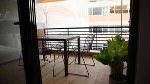 A balcony with a table and chairs, a potted plant, and a view of buildings. - Super Stylish Apartments in the heart of Athens (Athens)