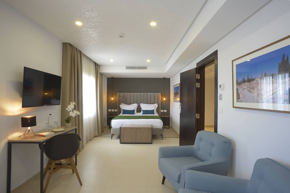 Une chambre d’hôtel avec un lit, un bureau, une chaise et un tél éviseur.
