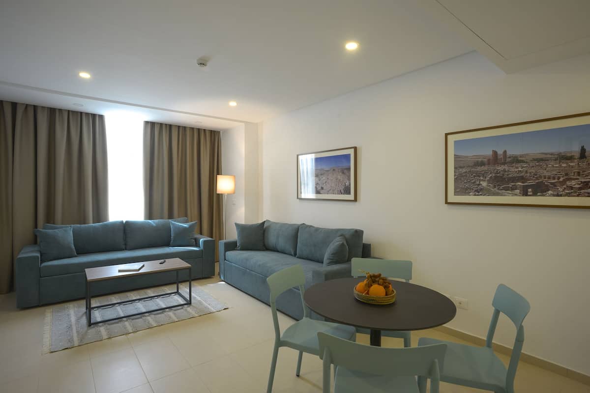 Un salon moderne avec deux canapés, une table basse et une table à manger avec des chaises. Deux tableaux encadrés sont accrochés au mur.