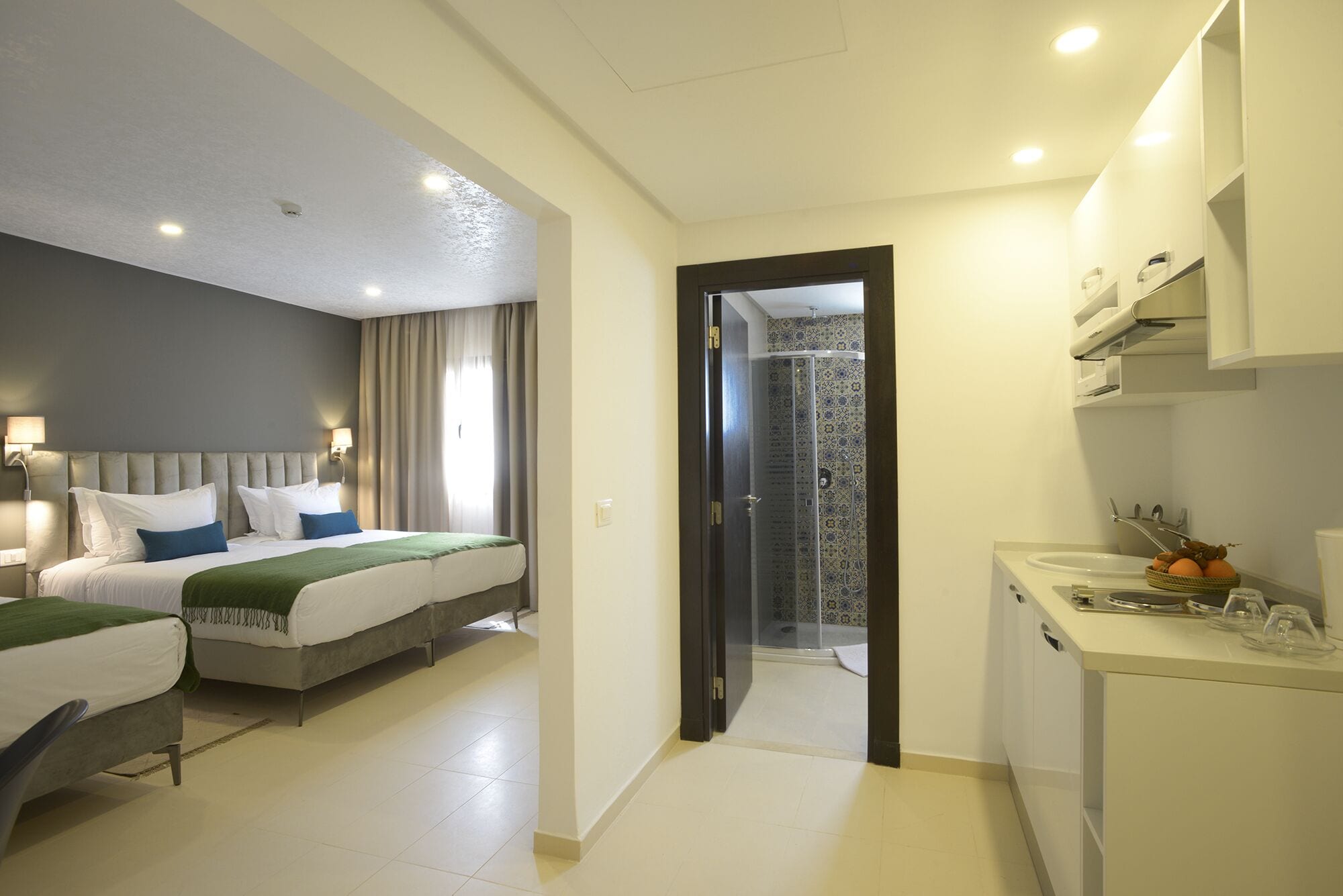Een hotelkamer met twee bedden, een badkamer met douche en een kitchenette.