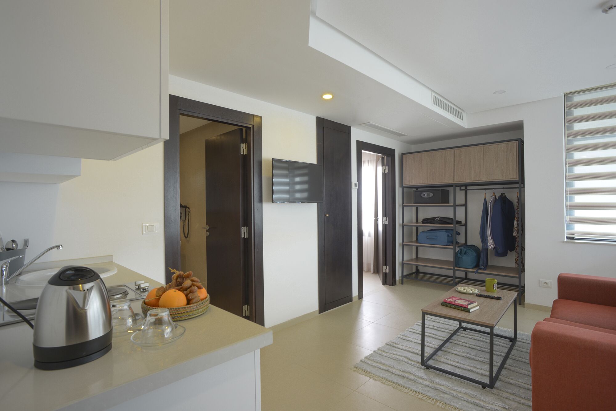 A modern living space with a kitchen area, a seating area with a coffee table, and a built-in wardrobe.