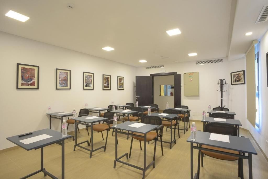 A classroom with desks arranged in rows, chairs, and educational posters on the walls.