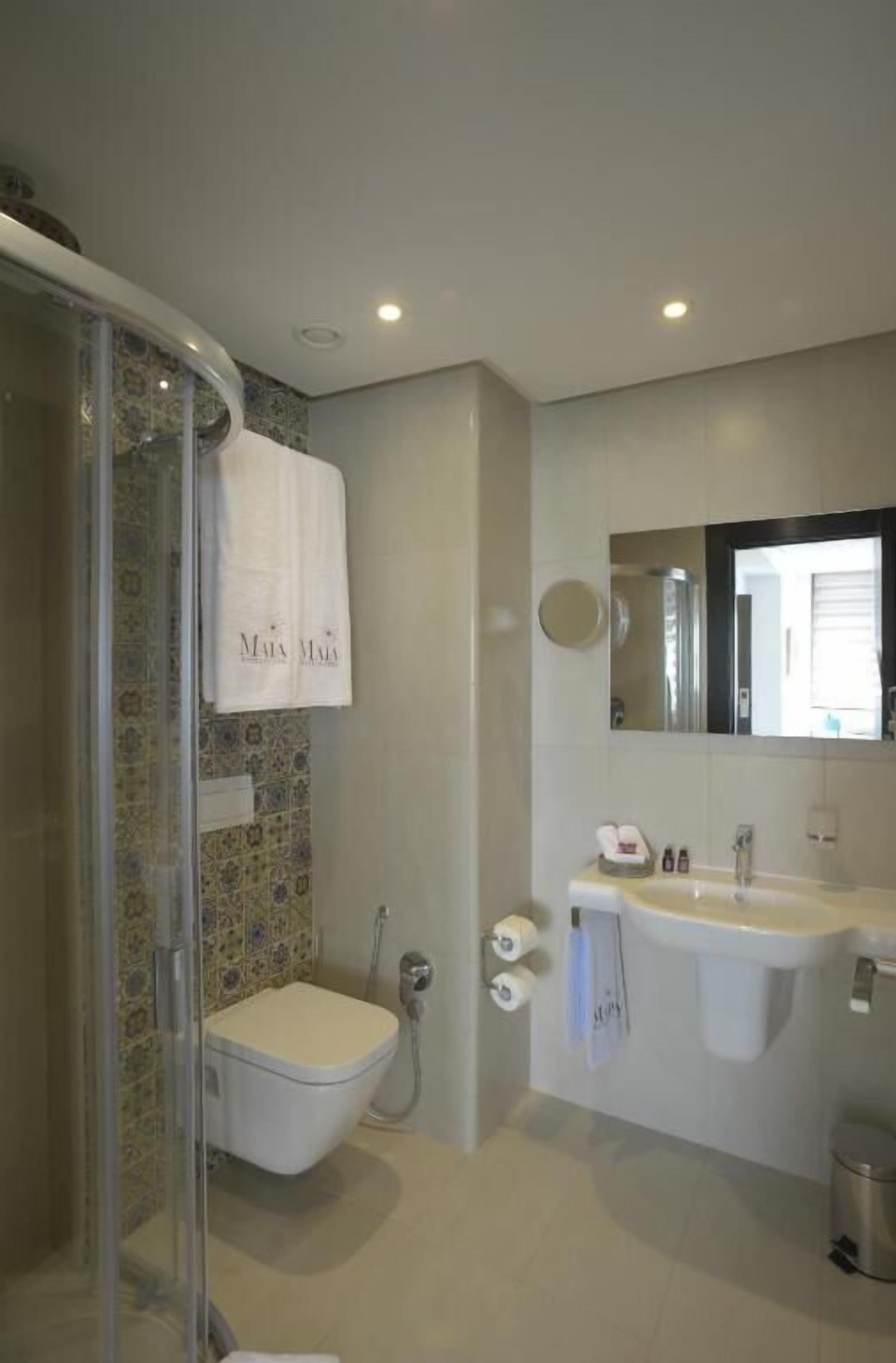 A bathroom with a shower, toilet, sink, and a towel hanging on the wall.