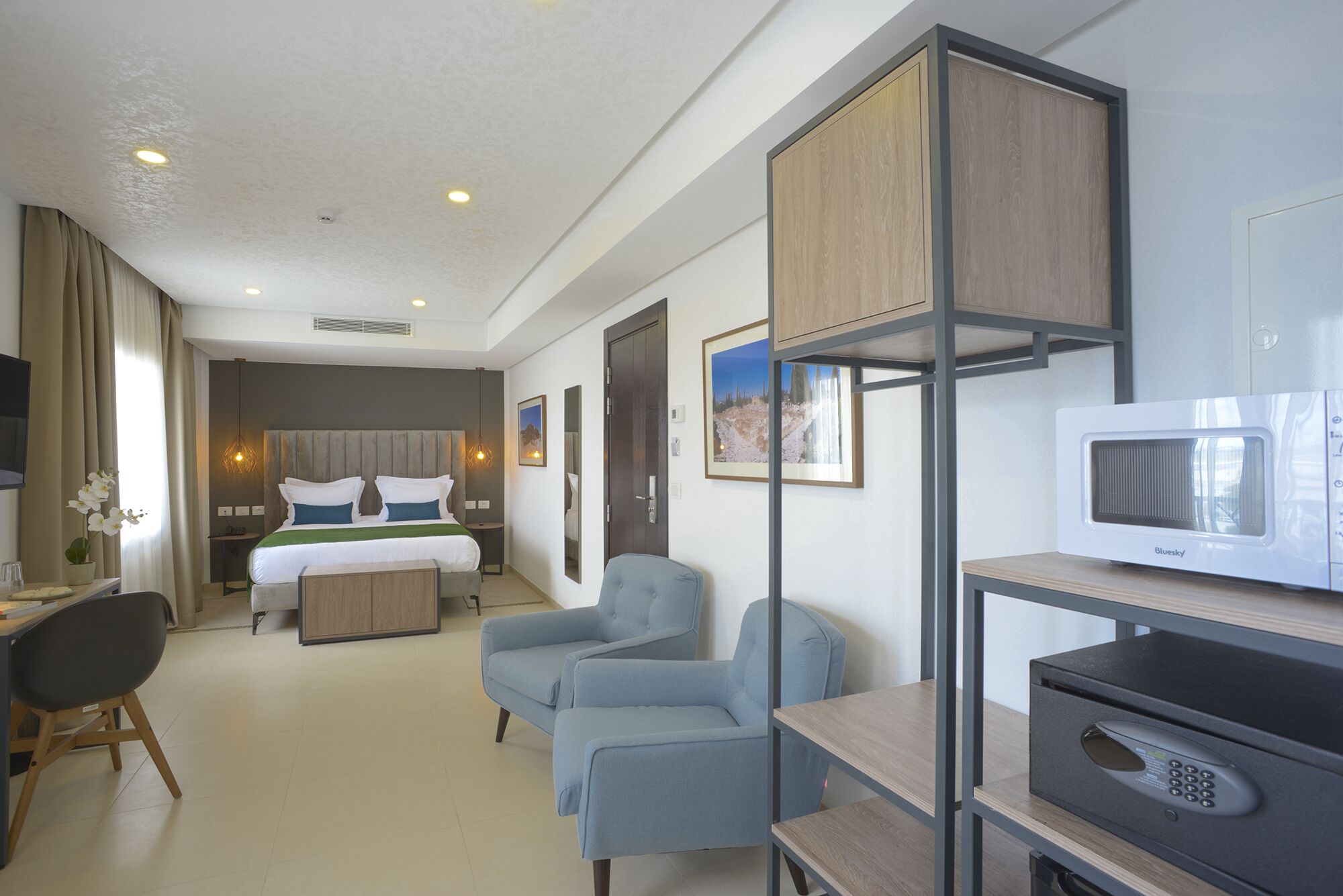 Camera d'albergo con letto, angolo salotto e angolo cottura.