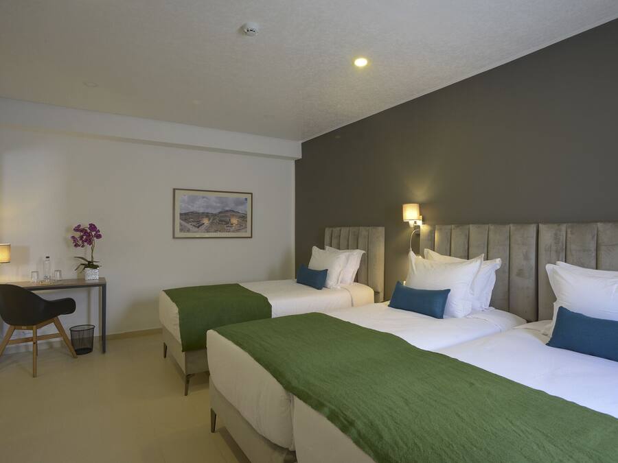Habitación de hotel con dos camas, un escritorio, una silla, una lámpara y un cuadro en la pared.