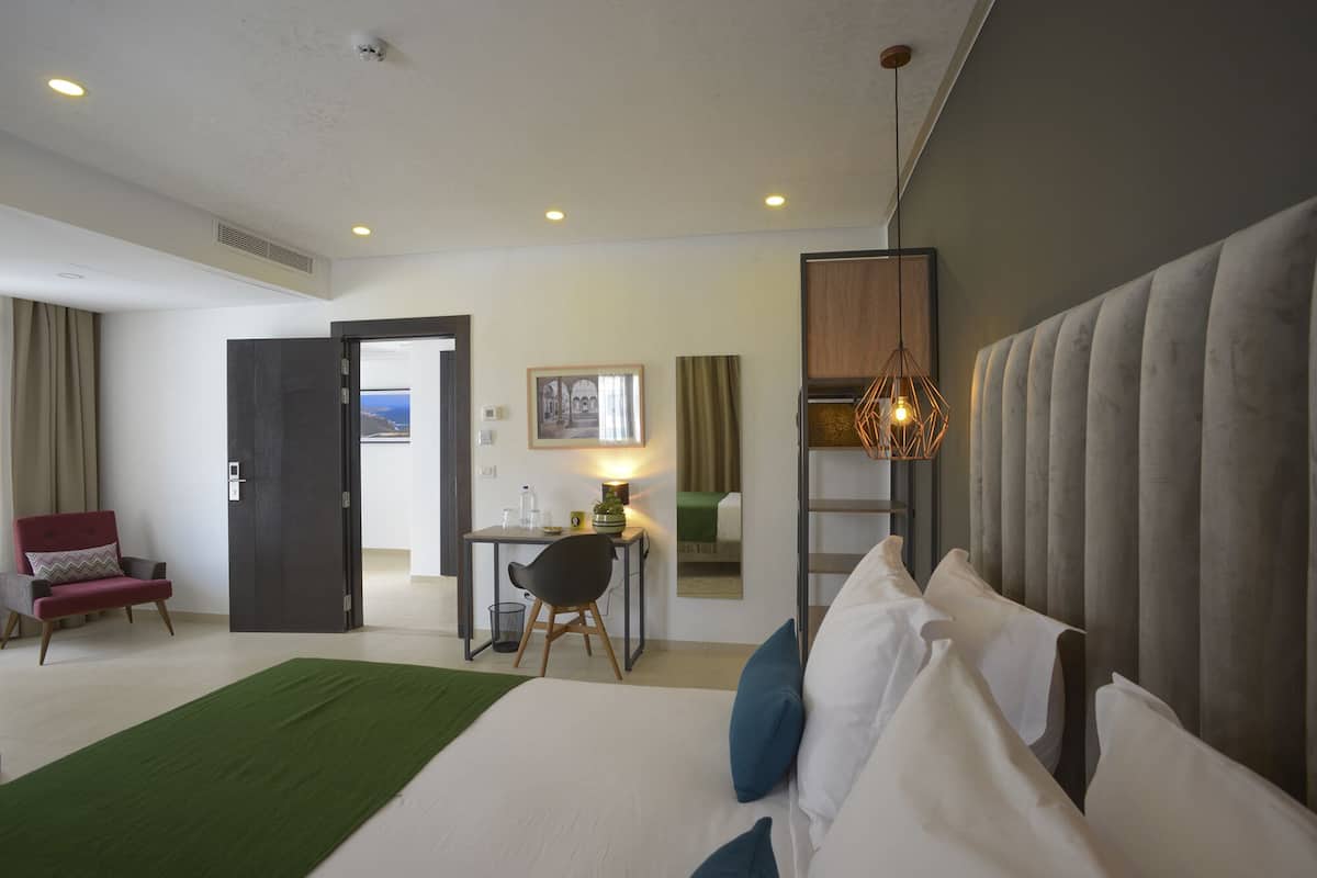 Une chambre d’hôtel équipée d’un lit, d’un bureau, d’une chaise, d’une lampe et offrant une vue sur l’extérieur.