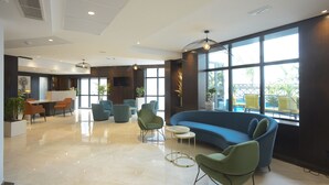 A spacious lobby with a blue sofa, green chairs, and a reception desk. - Maia Hotel Suites (Tunis)