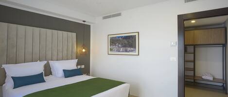 A bedroom with a bed, a green throw blanket, and a framed picture on the wall.
