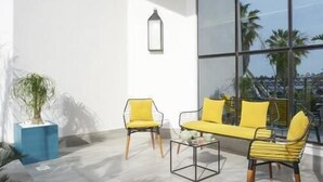 A modern outdoor seating area with a yellow sofa and chairs, a small table, and a potted plant. - Maia Hotel Suites (Tunis)