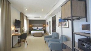 A modern hotel room with a bed, desk, chairs, and a TV. - Maia Hotel Suites (Tunis)