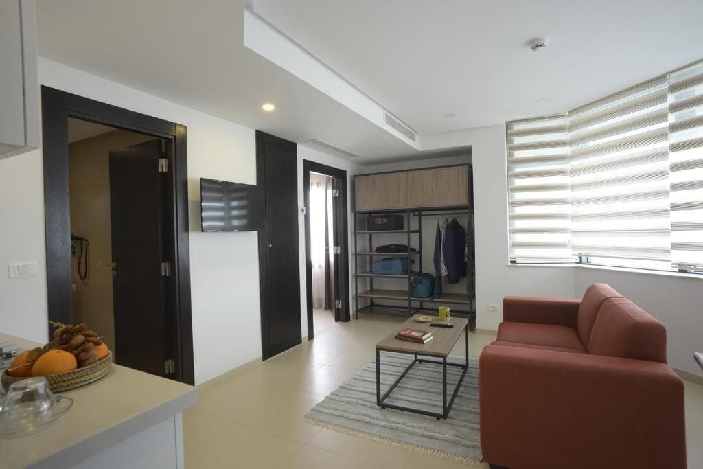 A modern living room with a sofa, a coffee table, and a kitchen area in the background.