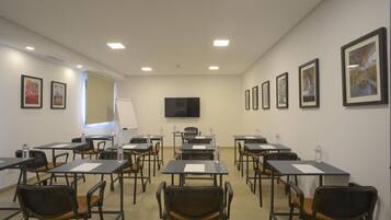 A conference room with tables and chairs, a whiteboard, and framed pictures on the walls.