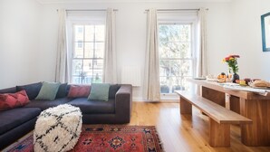 Een moderne woonkamer met een donkere bank, een houten bankje en een kamerkleed met een patroon.