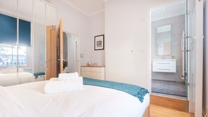 Een moderne hotelkamer met een groot bed, een badkamer met een douchecabine van glas en uitzicht op de straat.
