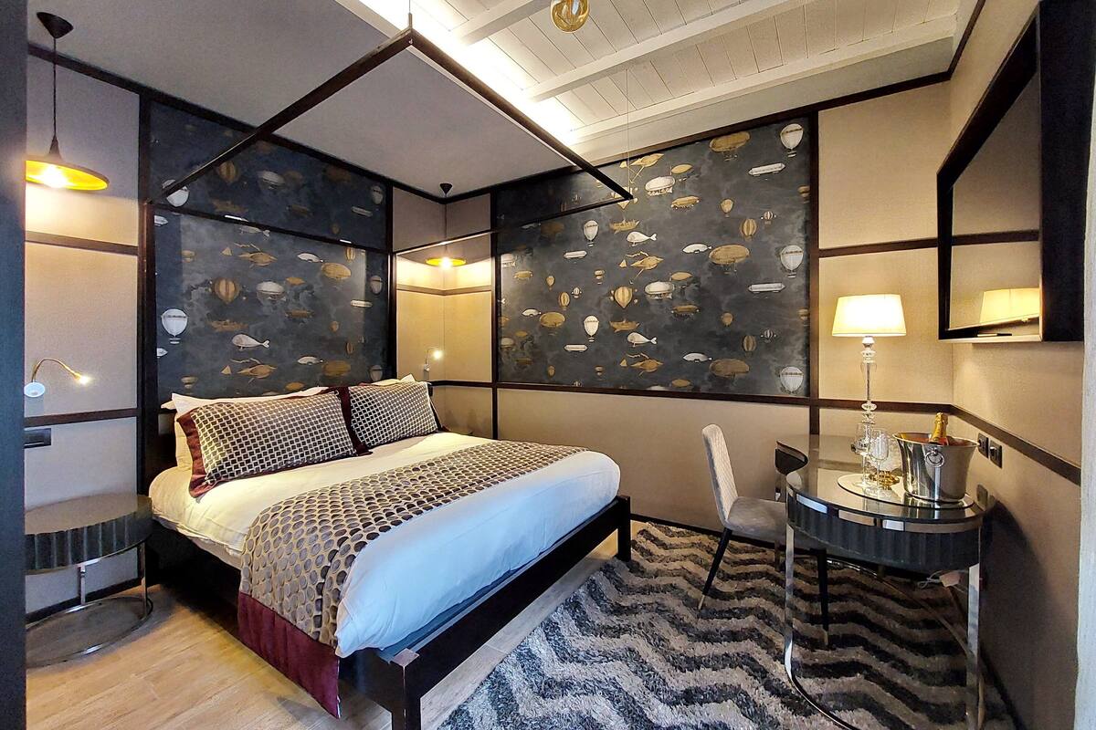Una habitación de hotel moderna con una cama grande, una mesita con una lámpara y un decorativo mural con peces.