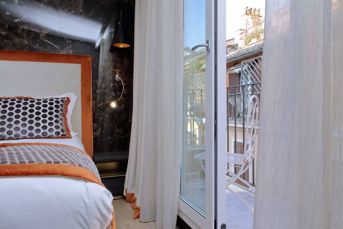 Un dormitorio con cama, ventana y balcón con sillas.