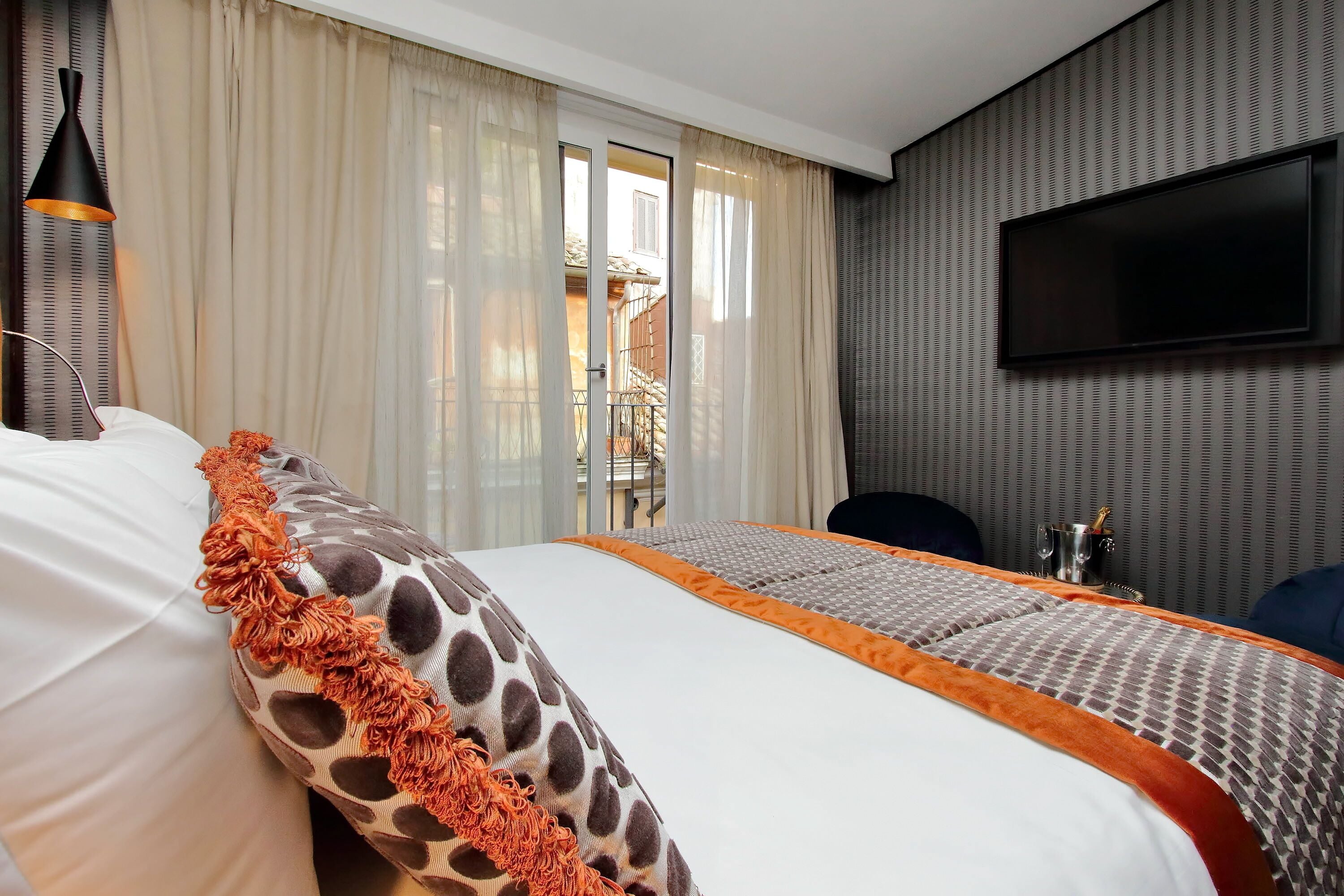A hotel room with a bed, curtains, a TV, and a view of the outside.