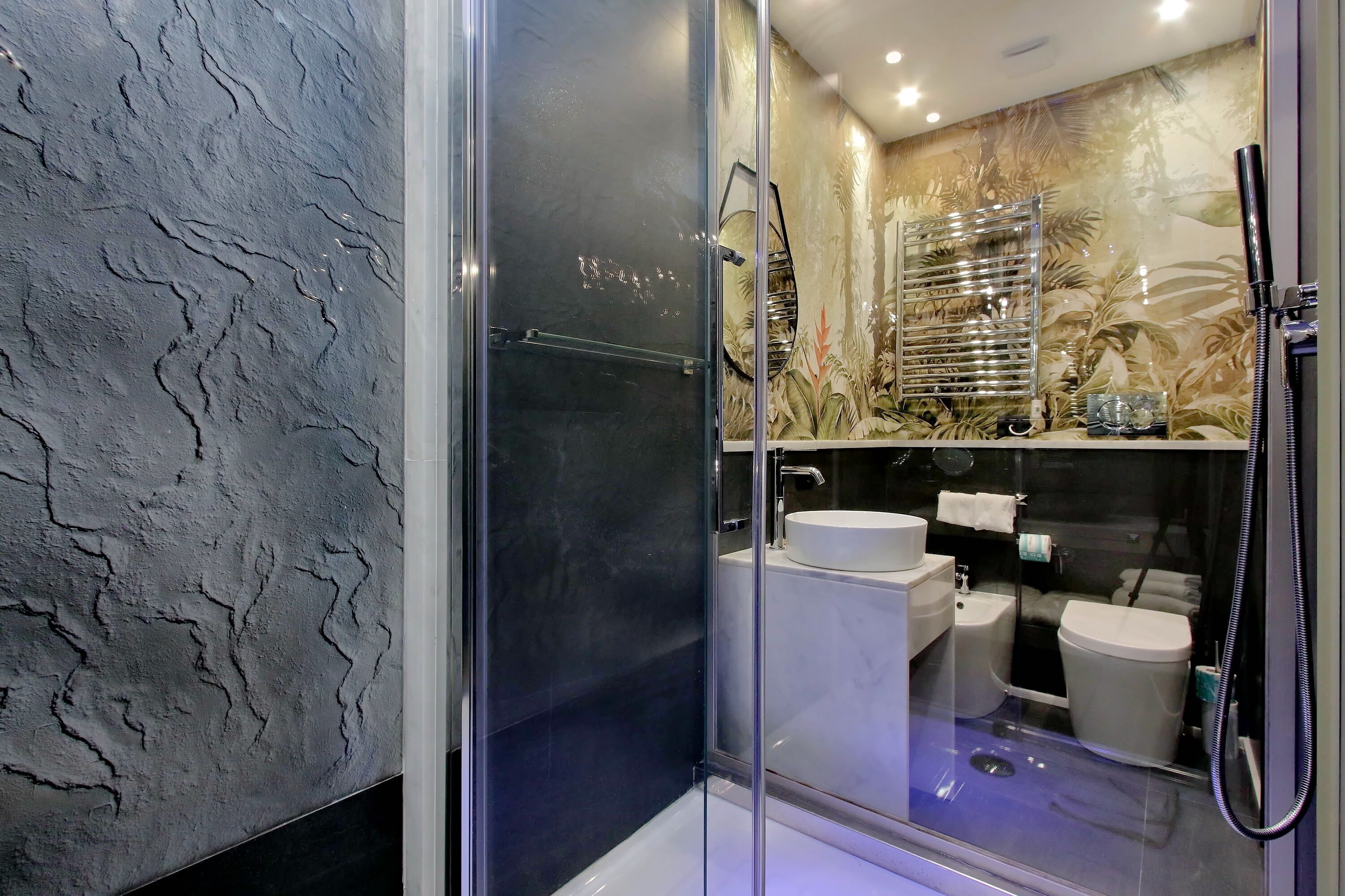 A modern bathroom with a glass-enclosed shower, a white sink, and a toilet.