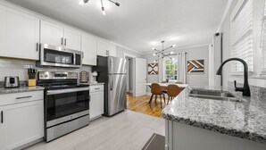 Una cocina moderna con electrodomésticos de acero inoxidable, armarios blancos y encimera de granito.