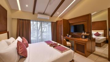 A hotel room with a large bed, a desk, a television, and a mirror.