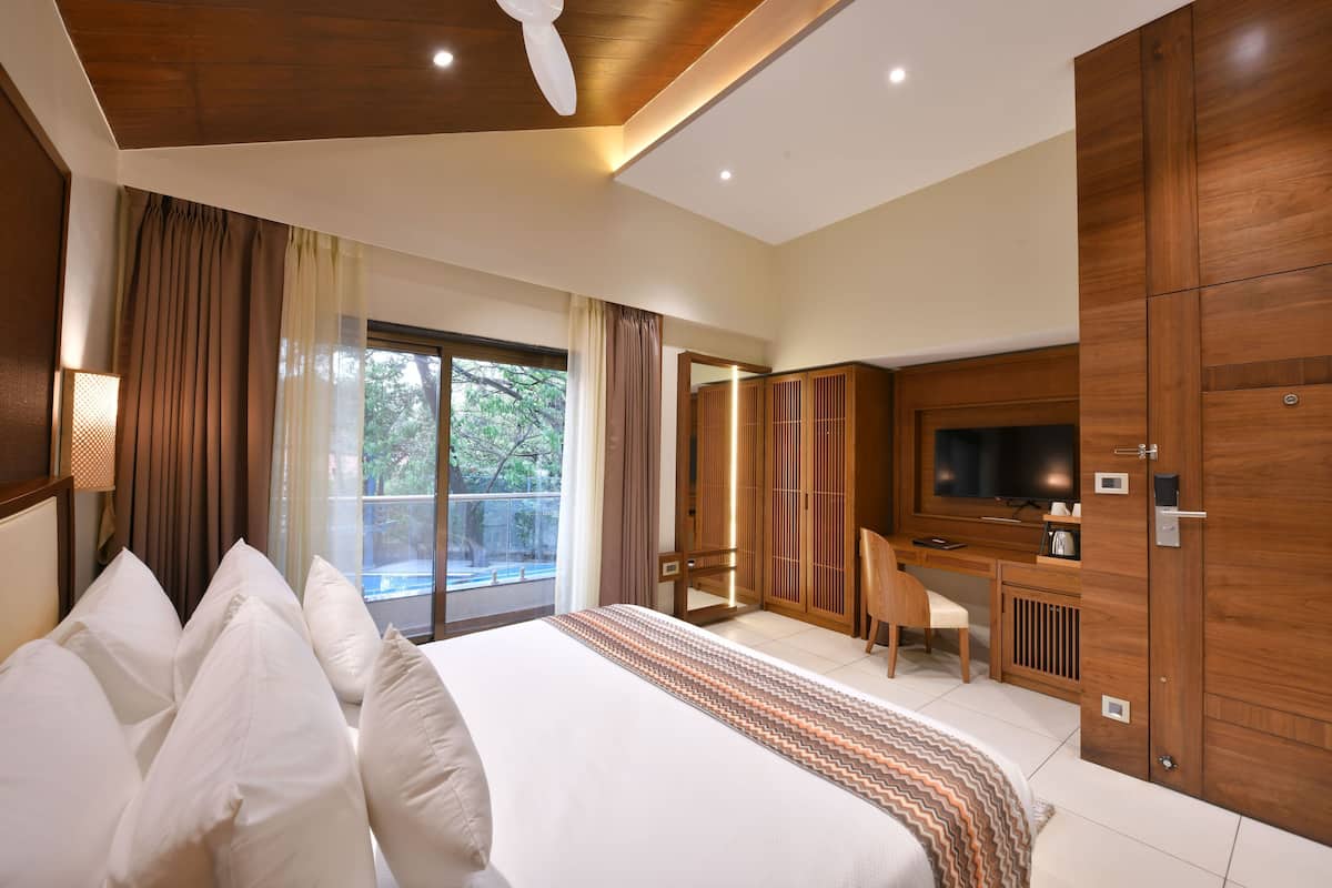 A modern hotel room with a large bed, a desk, and a TV.