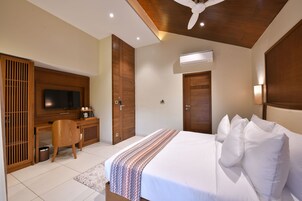 Una habitación de hotel con cama, escritorio con televisor y armario.