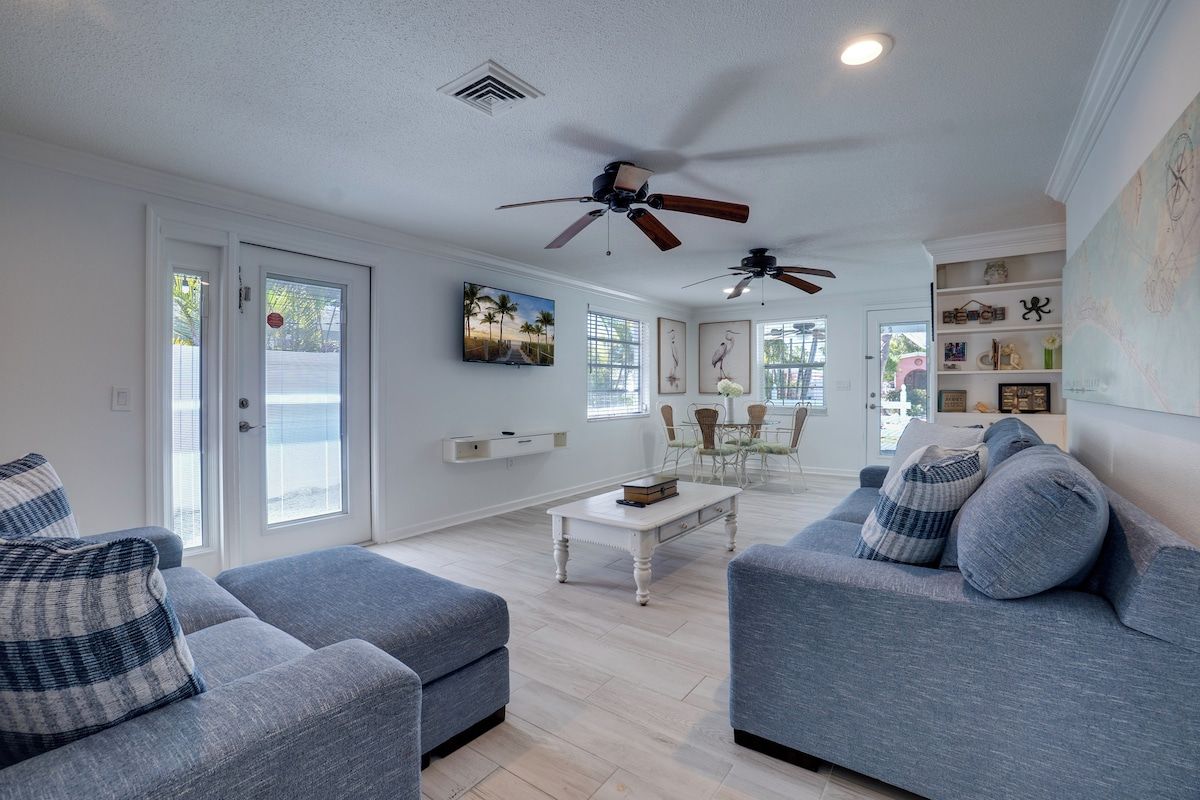 A modern living room with two grey sofas, a white coffee table, and ceiling fans.