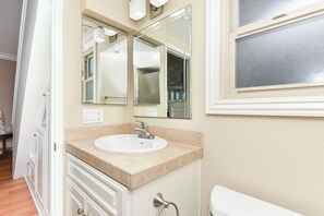 A bathroom with a white sink, a mirror, and a toilet. - Oceanfront 3 Bed 3 Bath Duplex on 60th St (Newport Beach)