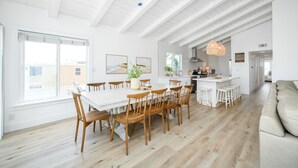 Een ruime keuken met een groot eiland, houten stoelen en een eettafel.