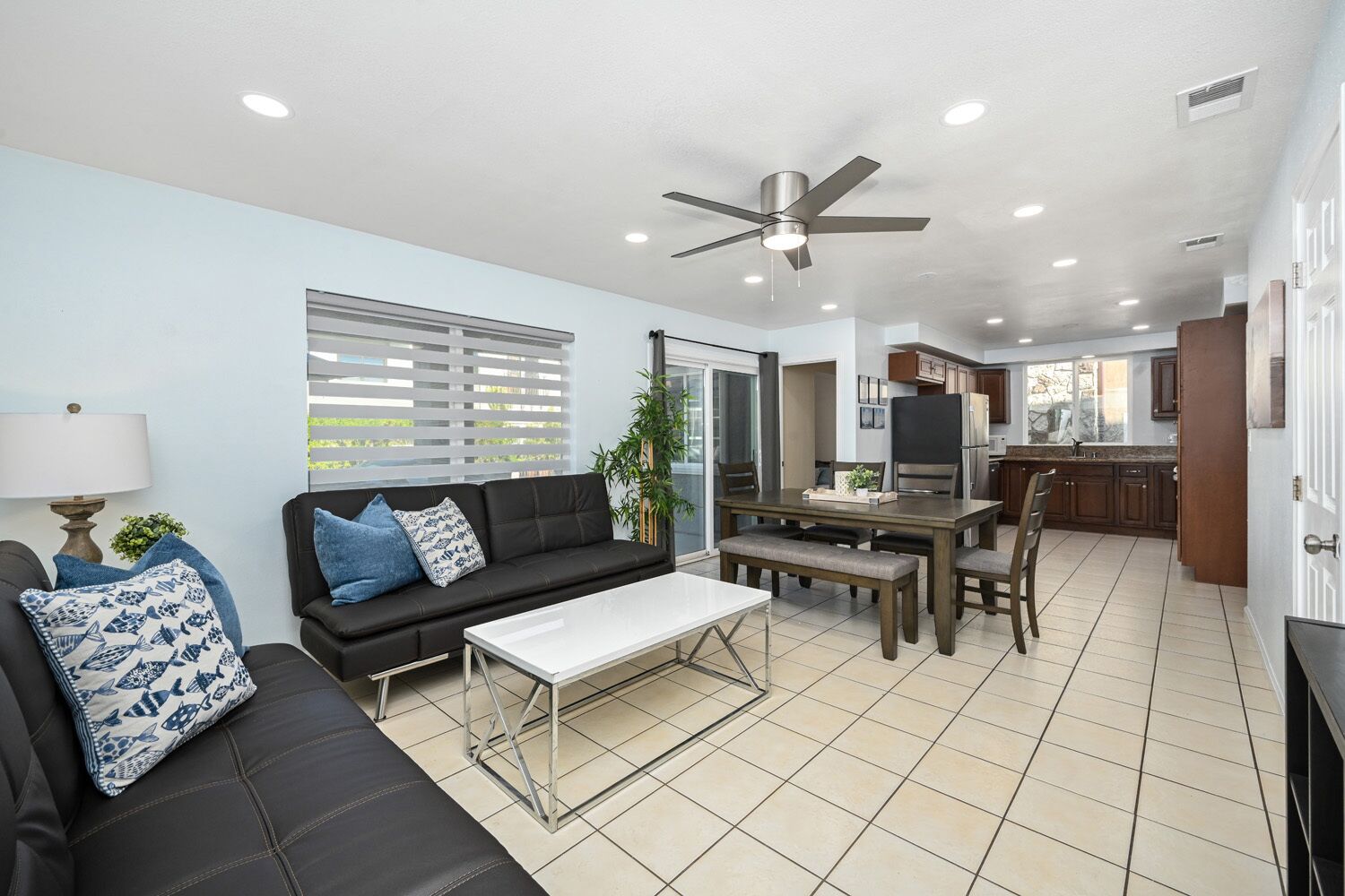 A modern living room with a black sofa, a white coffee table, and a dining area with a table and chairs.