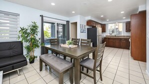 Una cocina moderna con armarios de madera, un refrigerador negro y un comedor con mesa y sillas.