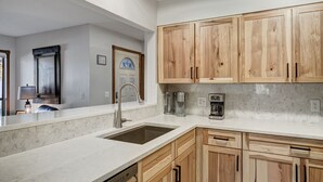 A kitchen with wooden cabinets, a stainless steel sink, and a coffee maker.