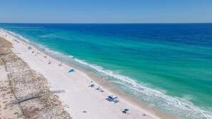 Une plage de sable blanc, une eau turquoise et limpide, et une jetée qui se dessine à l’horizon.