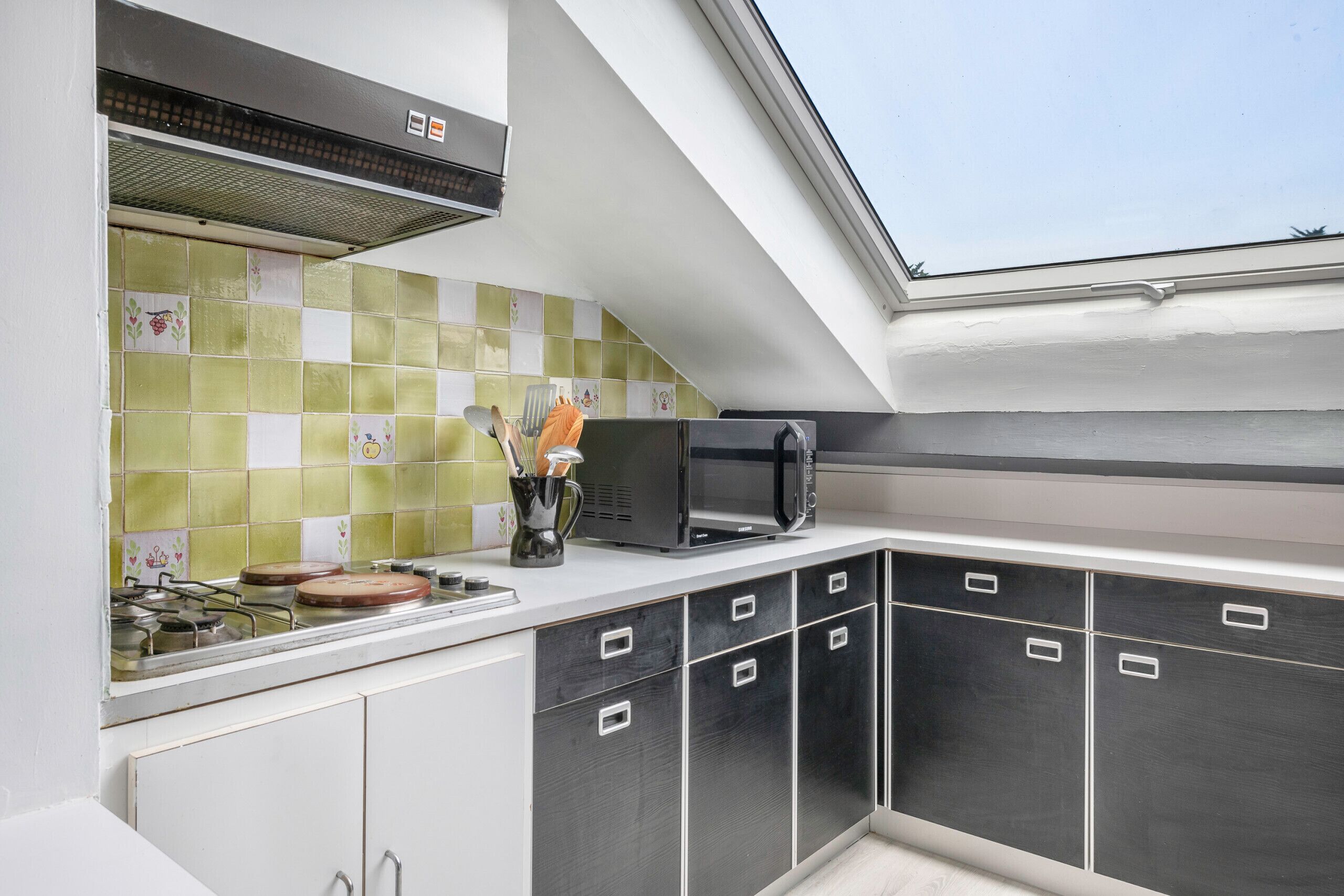 A kitchen with a gas stove, microwave, and a window above the sink.