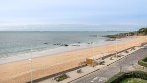 Een kustweg met een strand aan de ene kant en een rotsachtige landtong aan de andere kant.