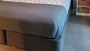 A bedroom with a large bed, two bedside tables, a wall-mounted TV, and a small wall decoration. - Suburbia East Auckland (Auckland)