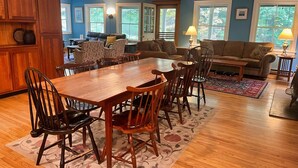A dining area with a wooden table and chairs, a sofa, and a patterned rug. - Edgewood, Beautiful custom built 5 bdrm home w/ fire pit, game room, scenic pond (Milford)