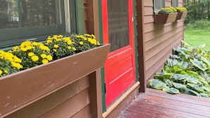A wooden house with a red door, windows with green shutters, and flower boxes on the porch. - Edgewood, Beautiful custom built 5 bdrm home w/ fire pit, game room, scenic pond (Milford)