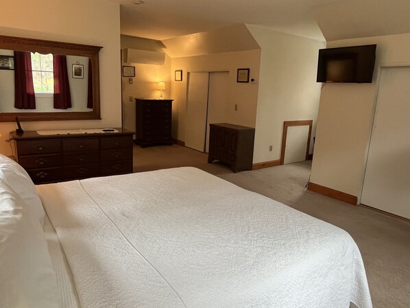Une chambre à coucher avec un grand lit, une commode et une armoire.