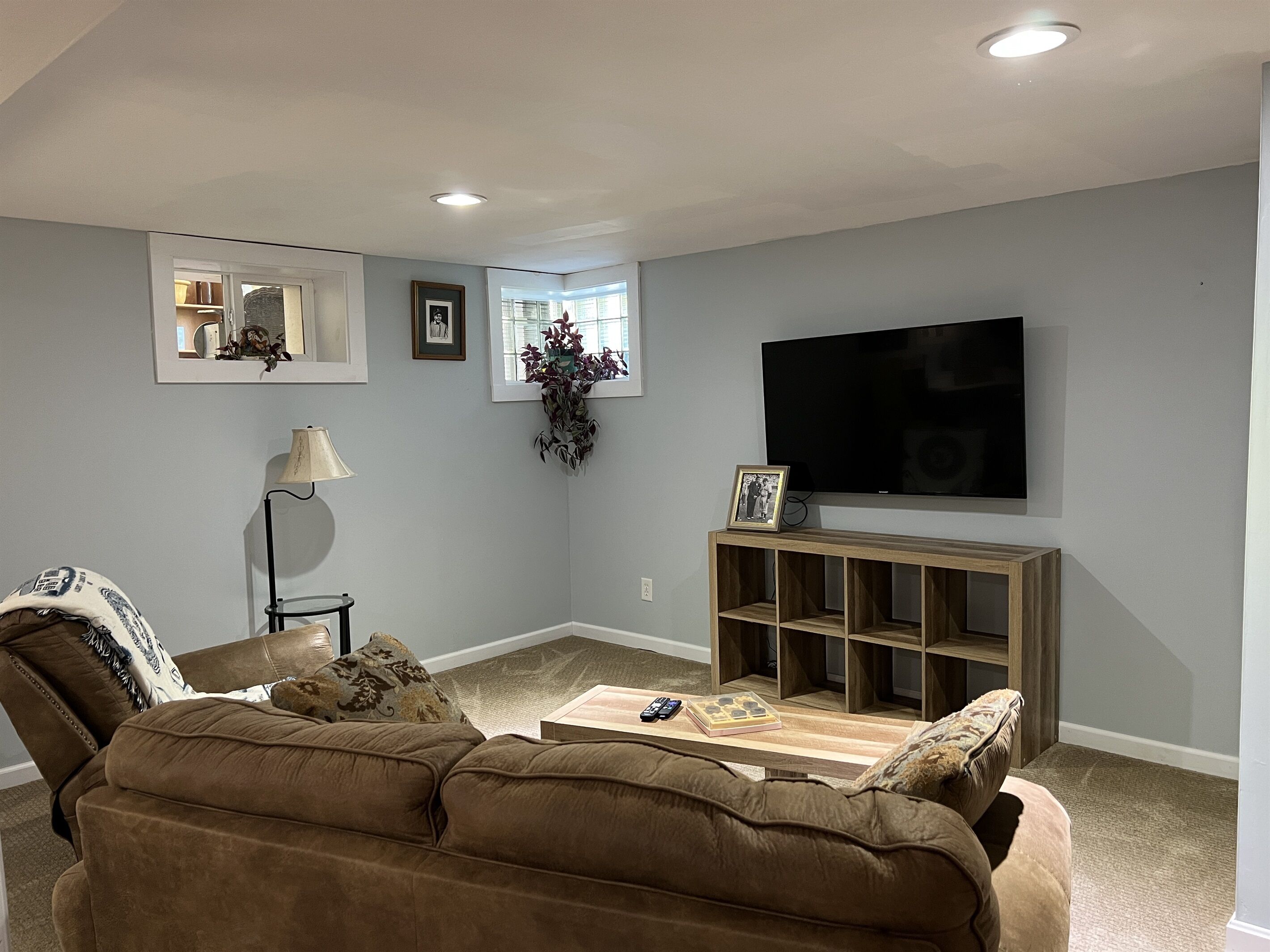 A living room with a brown sofa, a coffee table, a TV, and a wooden TV stand.
