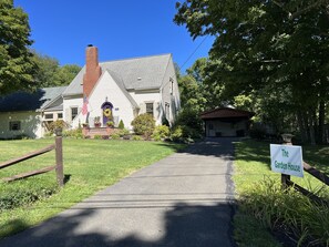 A house with a paved driveway leading to the entrance, surrounded by greenery and a sign reading "The Garden House". - Garden House - Close to All Star Village, beautiful gardens, game room (Oneonta)