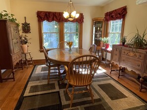 A dining area with a wooden table, chairs, a chandelier, and a patterned rug. - Garden House - Close to All Star Village, beautiful gardens, game room (Oneonta)